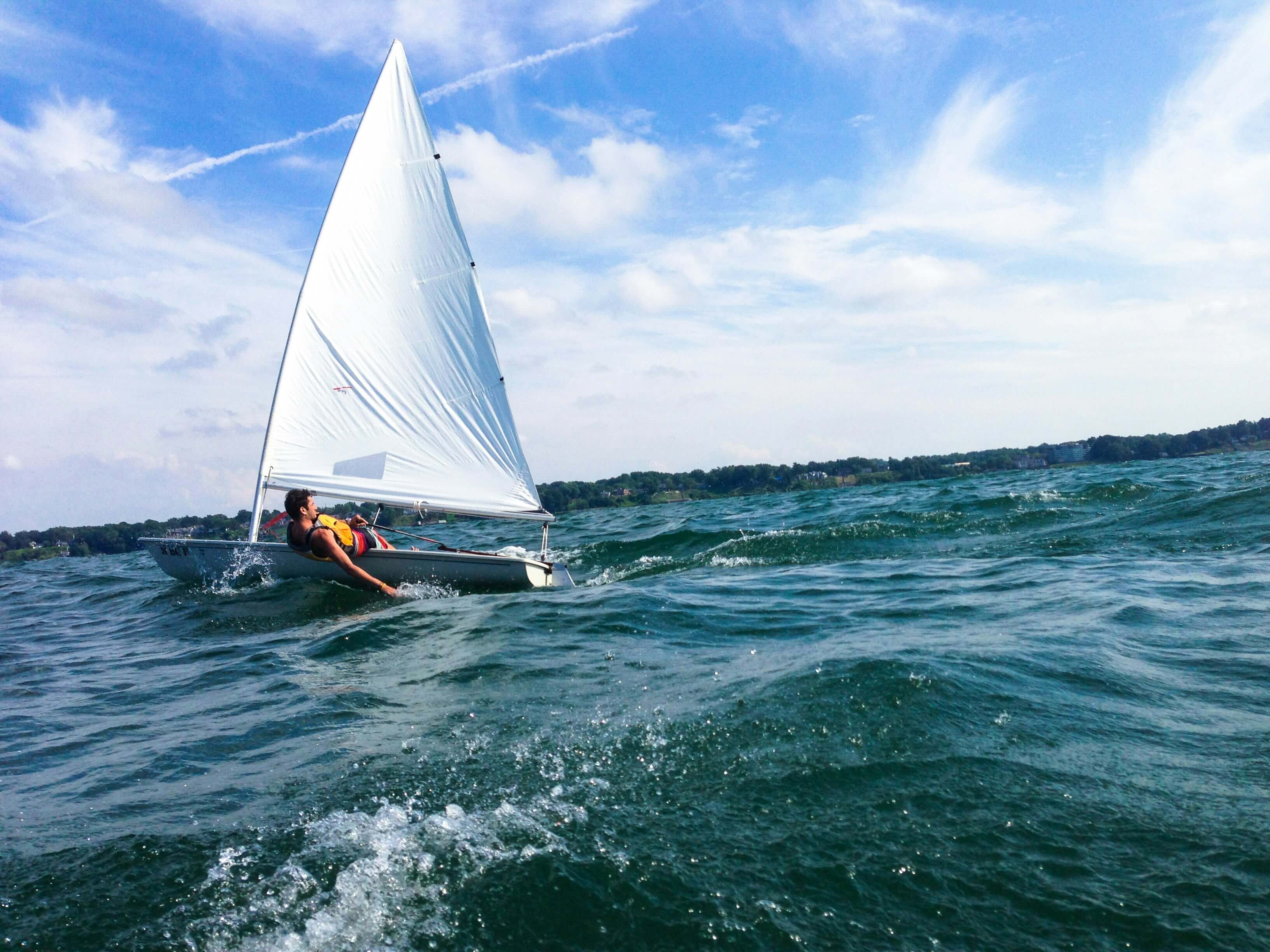 a person sailing on a one-person sailboat